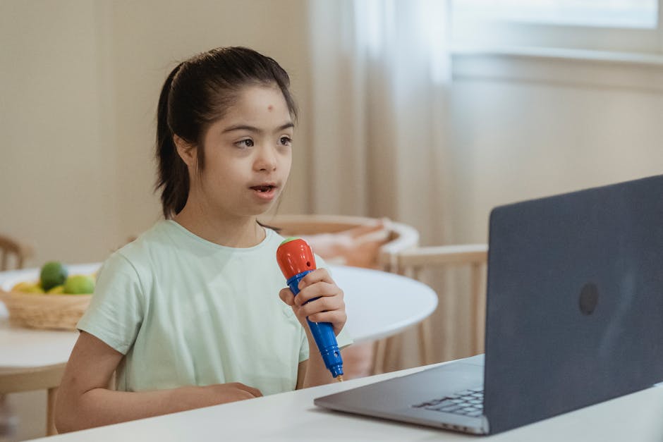 Child with Down syndrome interacts with a laptop and toy microphone at home.