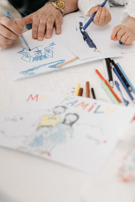 Child and adult hand drawing family pictures using colored pencils on paper.