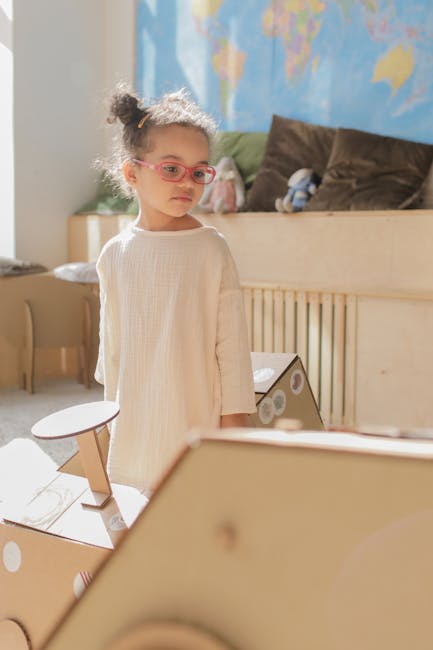 Young girl engaging in creative play with cardboard crafts in a bright classroom.